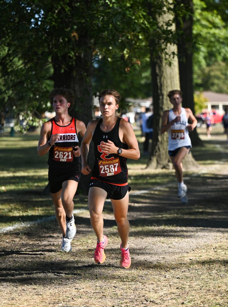 Senior Hugh Davis runs on a dirt trail near two other runners at the Granite City Invite