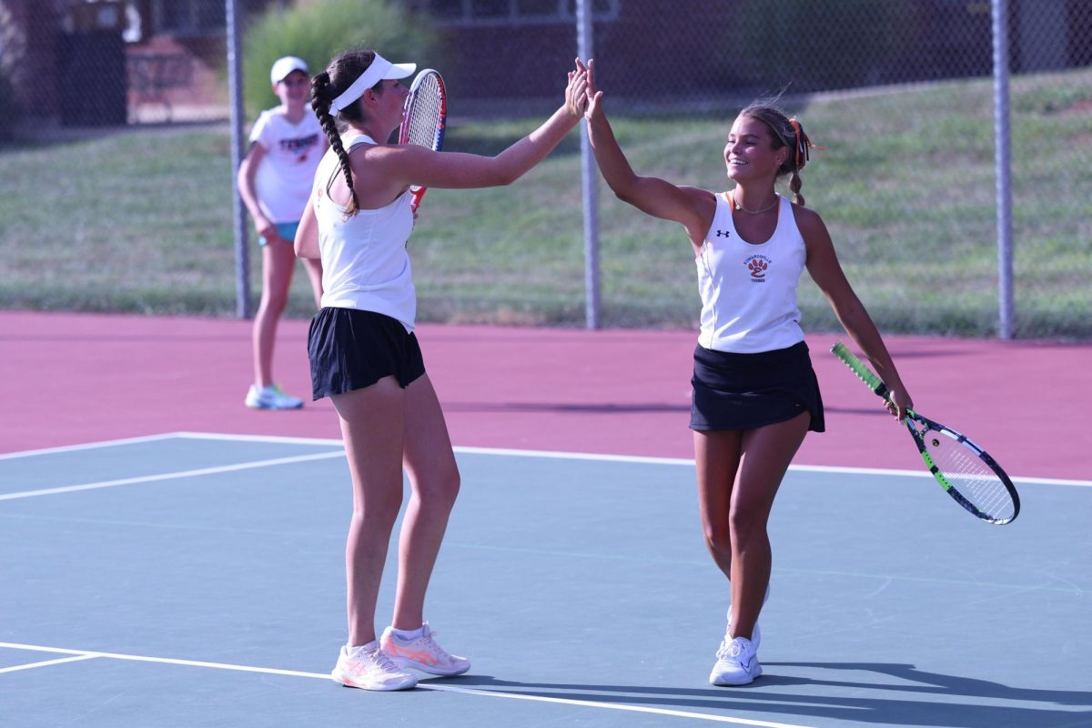 Senior Sophie Byron and junior Katie Woods high five after a point at the Heather Bradshaw Invite on Sept. 6