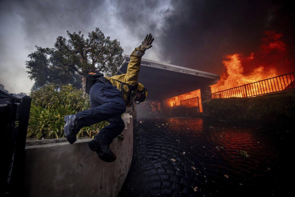 A firefighter vaults a wall into a burnt down house during the 2025 Californian fires 