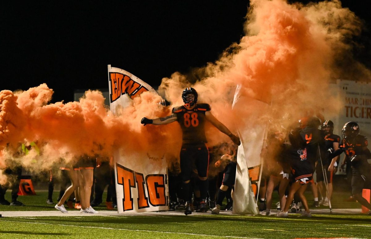 Senior Iose Epenesa runs through an Edwardsville tiger banner before the start of a football game on Oct. 28.